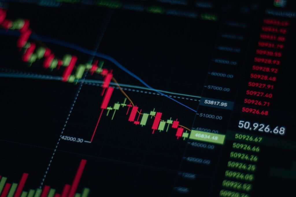 Stock market chart showing a downward trend, symbolizing a liquidity squeeze, with blurred logos of tech companies and cryptocurrencies.