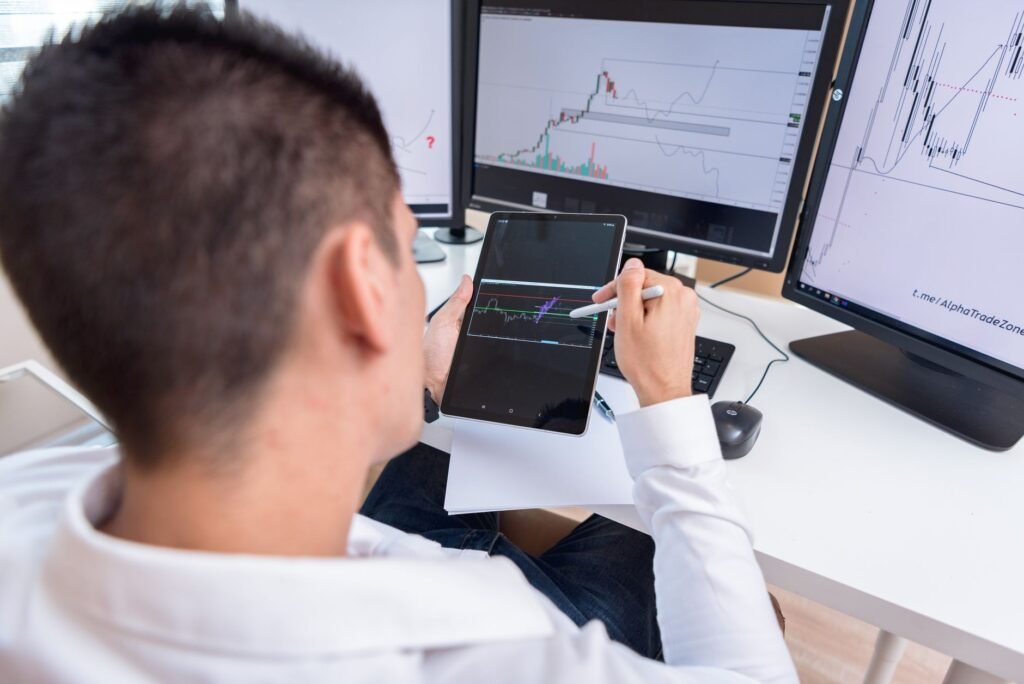 A focused individual working at a computer displaying cryptocurrency charts and market data.