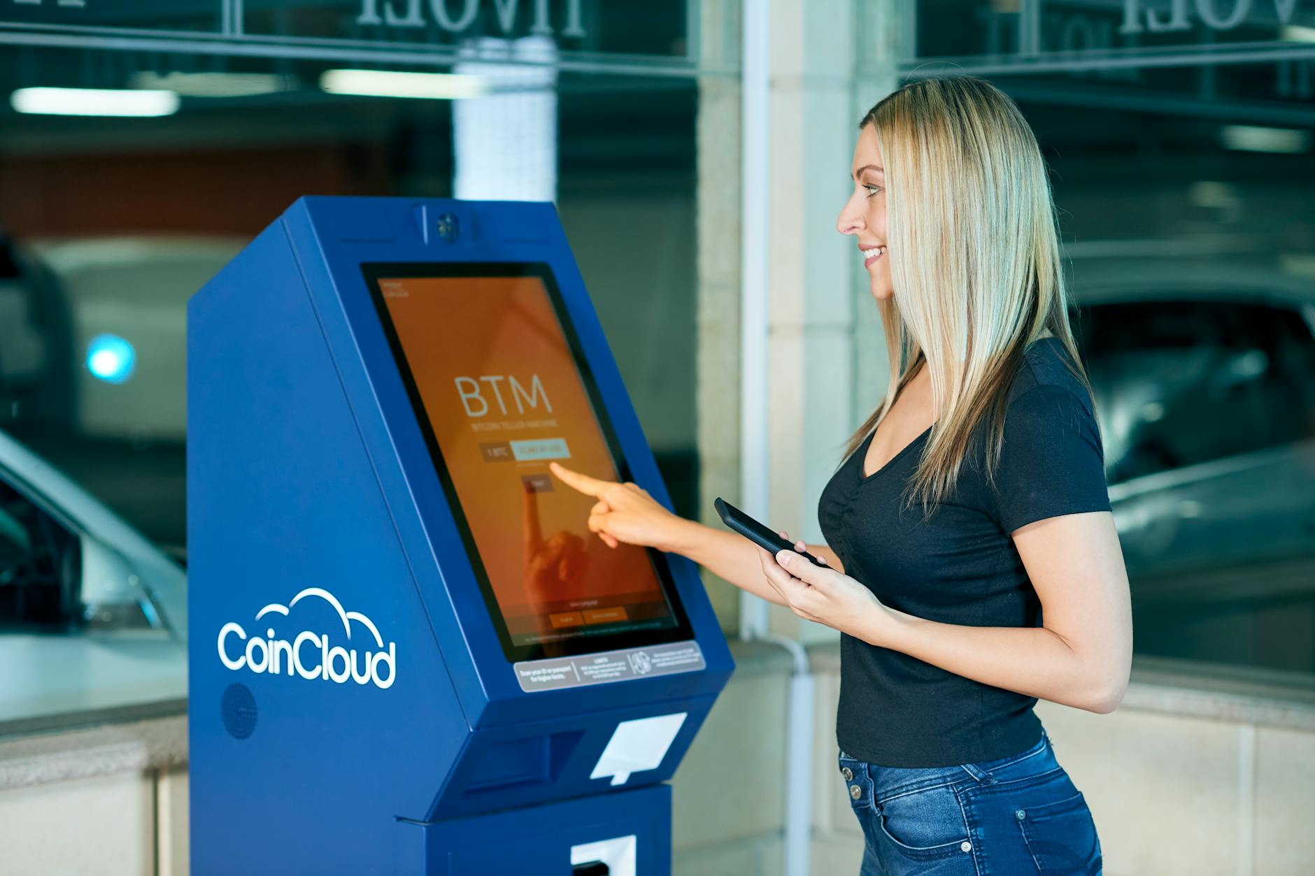 A woman interacts with a CoinCloud machine indoors, showcasing modern digital banking.