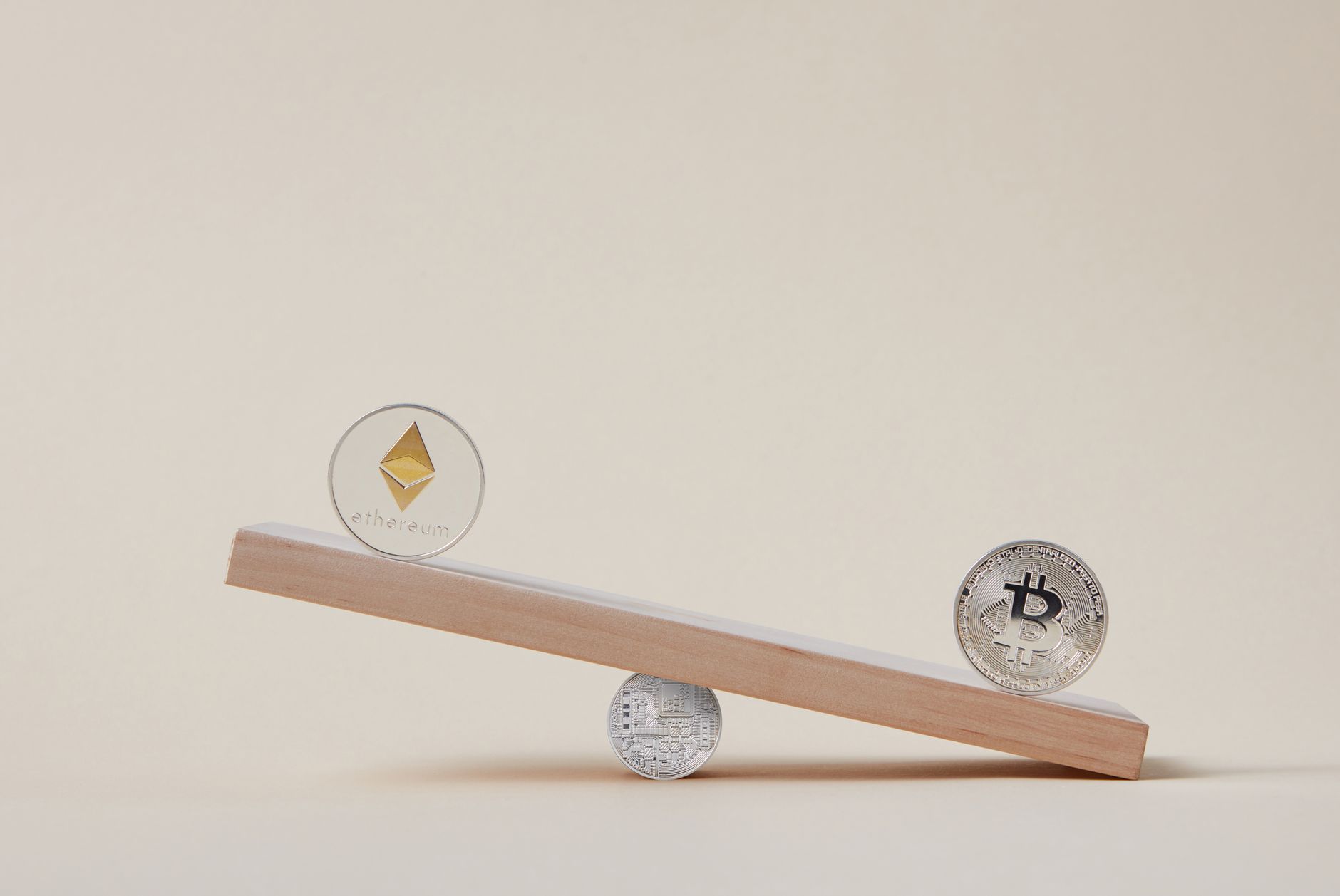 Minimalist image of Ethereum and Bitcoin coins balancing on a plank, symbolizing crypto market dynamics.