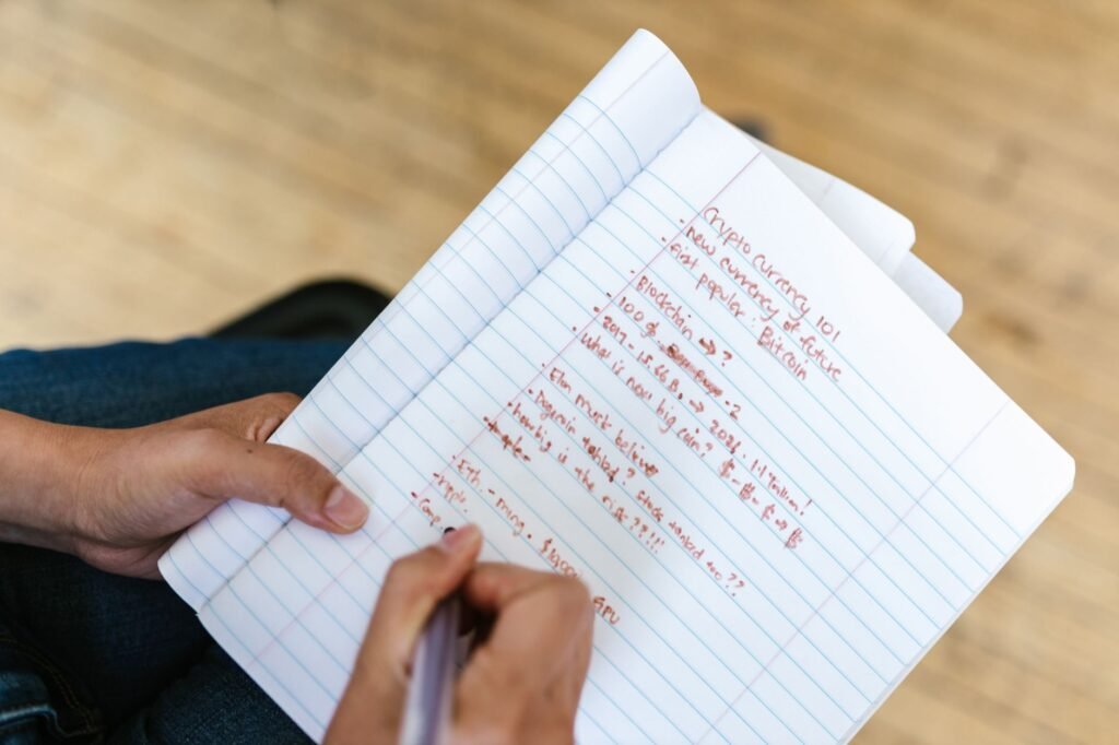 A person focused on a laptop screen with crypto charts, surrounded by research materials, symbolizing productive learning in the digital asset space.