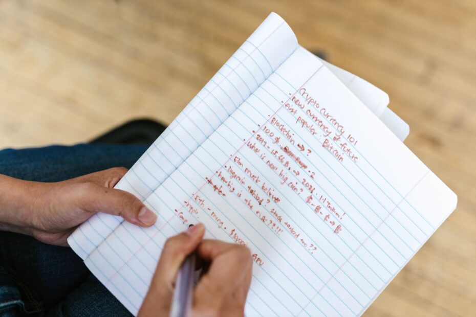 A person focused on a laptop screen with crypto charts, surrounded by research materials, symbolizing productive learning in the digital asset space.
