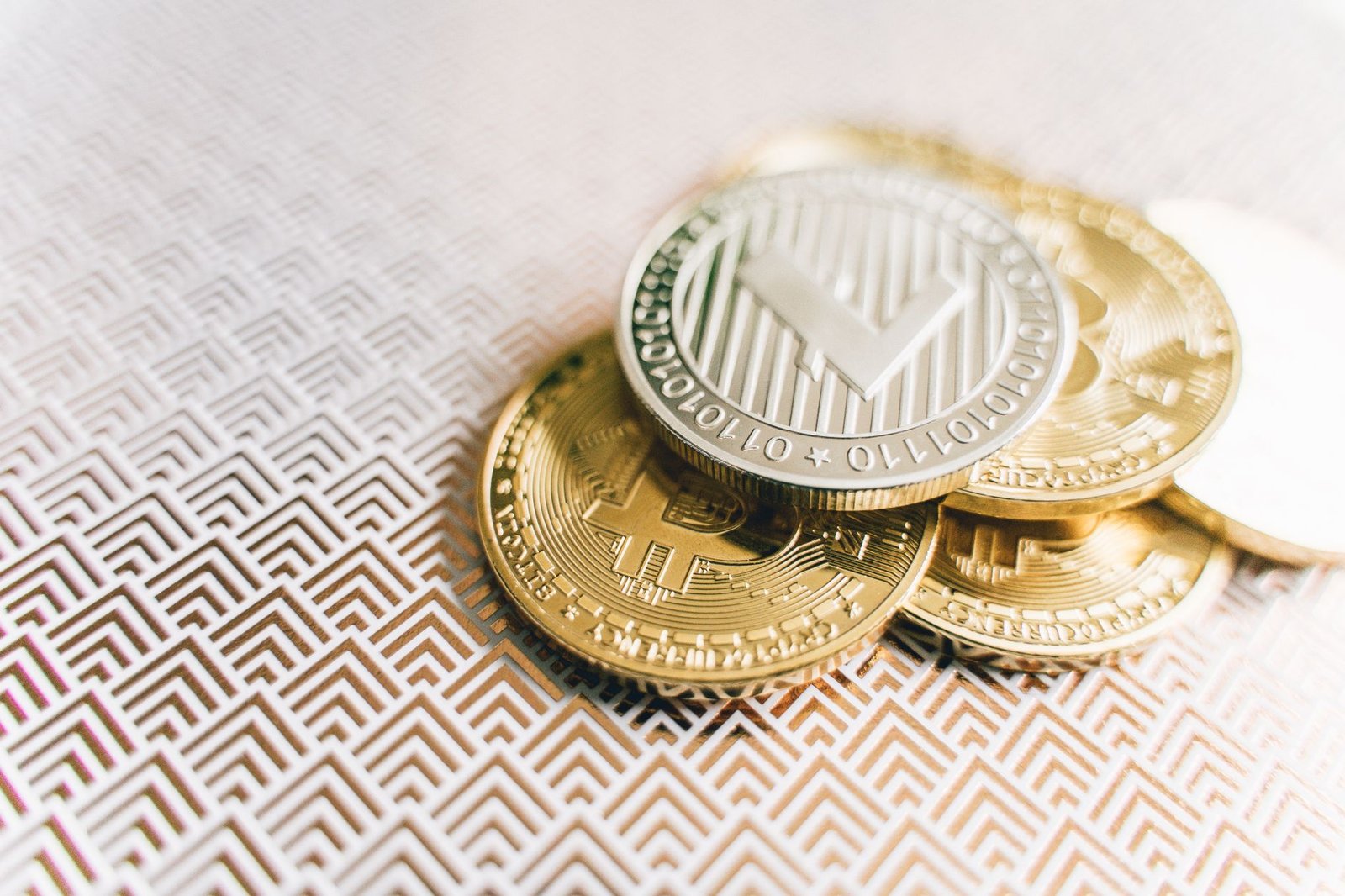 Stack of Bitcoin and Litecoin coins on a geometric textured surface, symbolizing digital finance.
