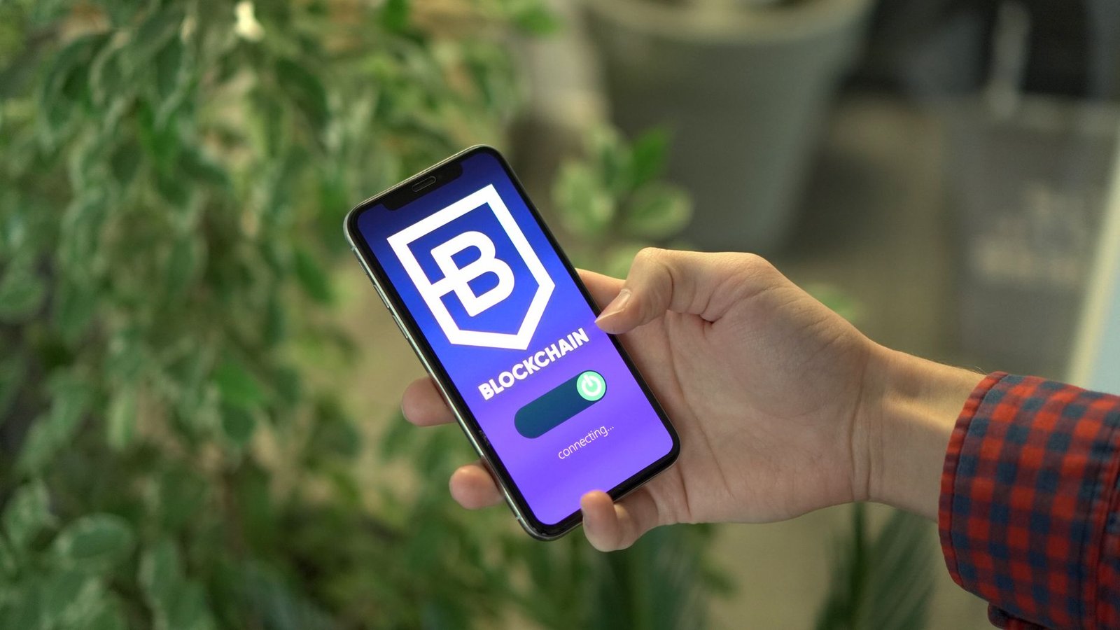 Close-up of a smartphone showing a blockchain app screen held by a hand.